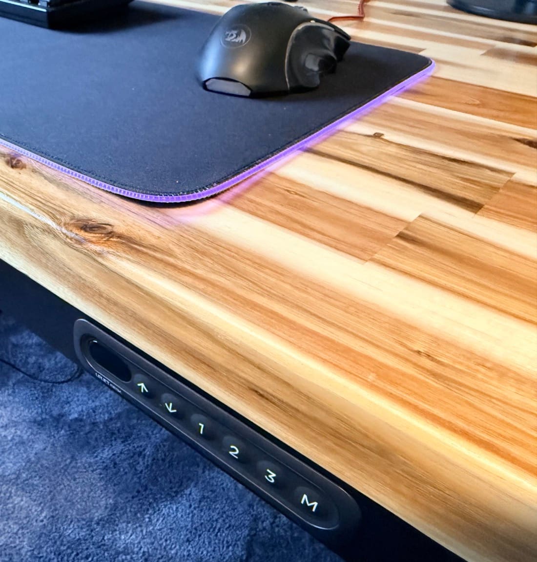 UPLIFT Parsons in daily use with desk mat and mouse, flush keypad embedded in the front apron and Acacia butcher block desktop