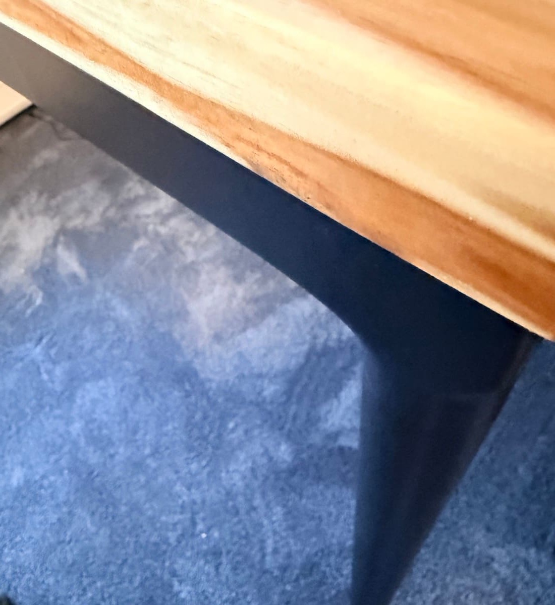 Single tapered Parsons leg meeting the floor, showing the slim profile and matte black finish