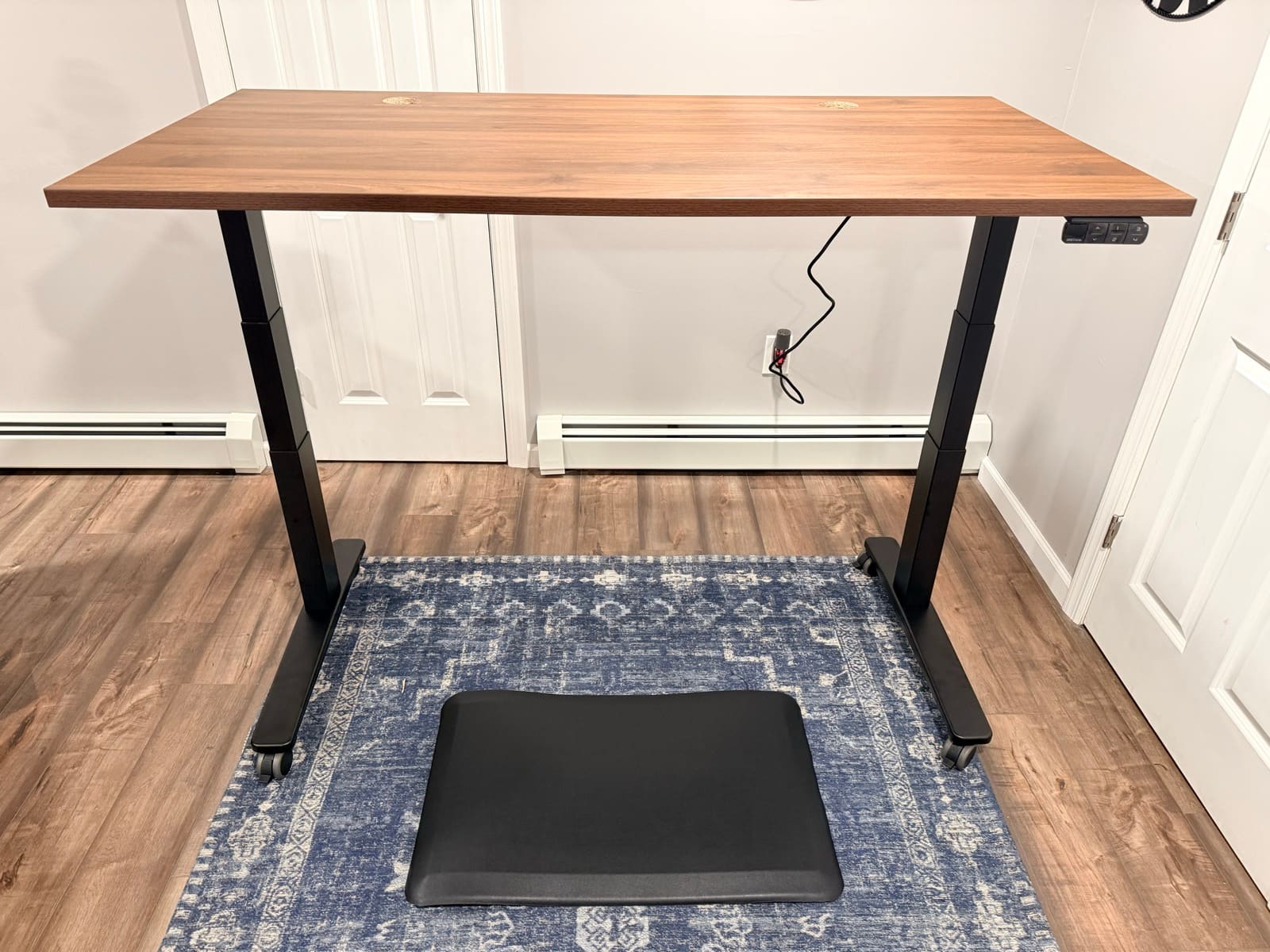 UPLIFT V3 Standing Desk assembled at standing height with walnut top, casters, and walking pad