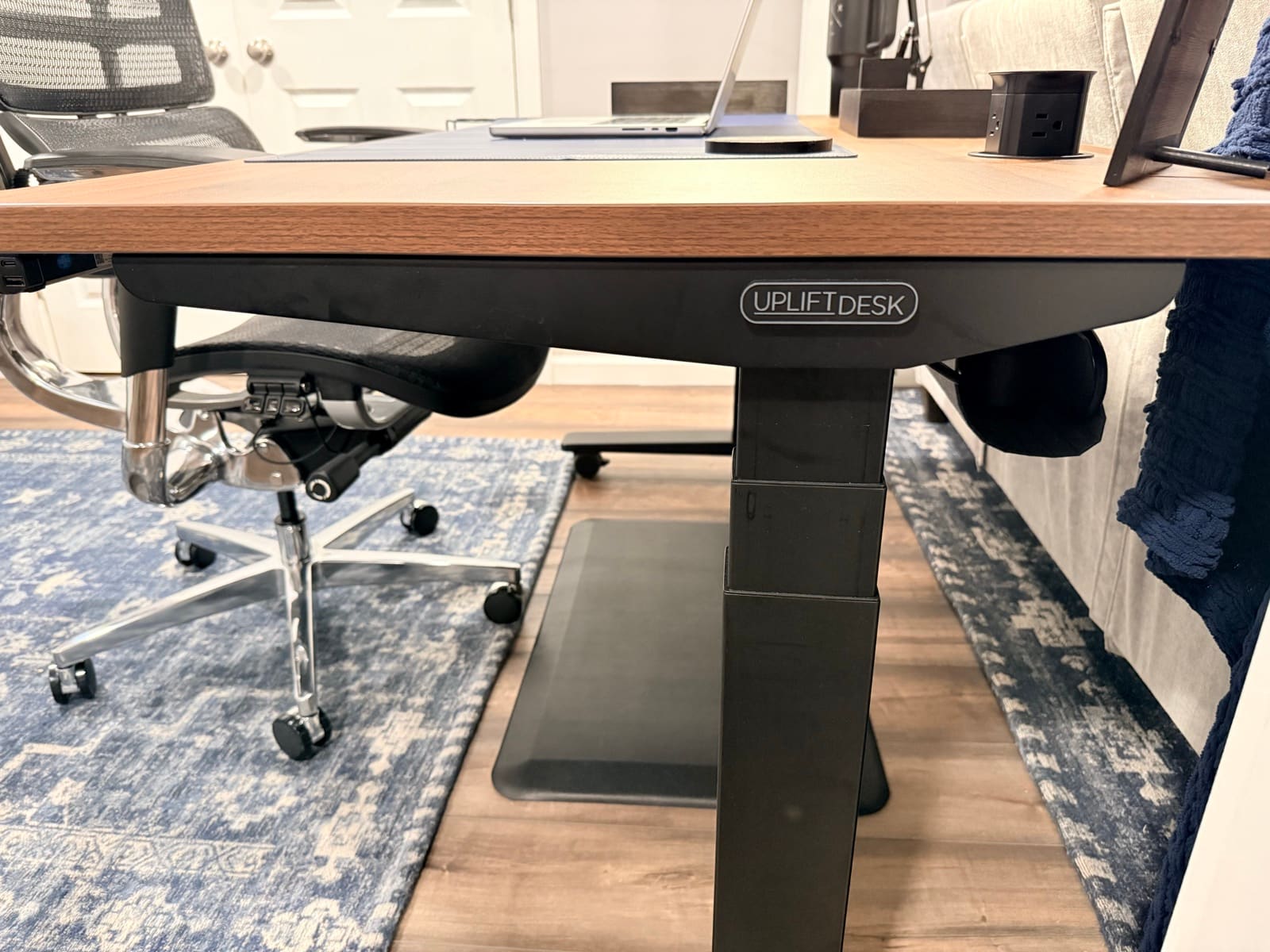 Under-desk view of the UPLIFT V3 showing the industrial steel frame, casters, and UPLIFT Desk logo on the crossbar