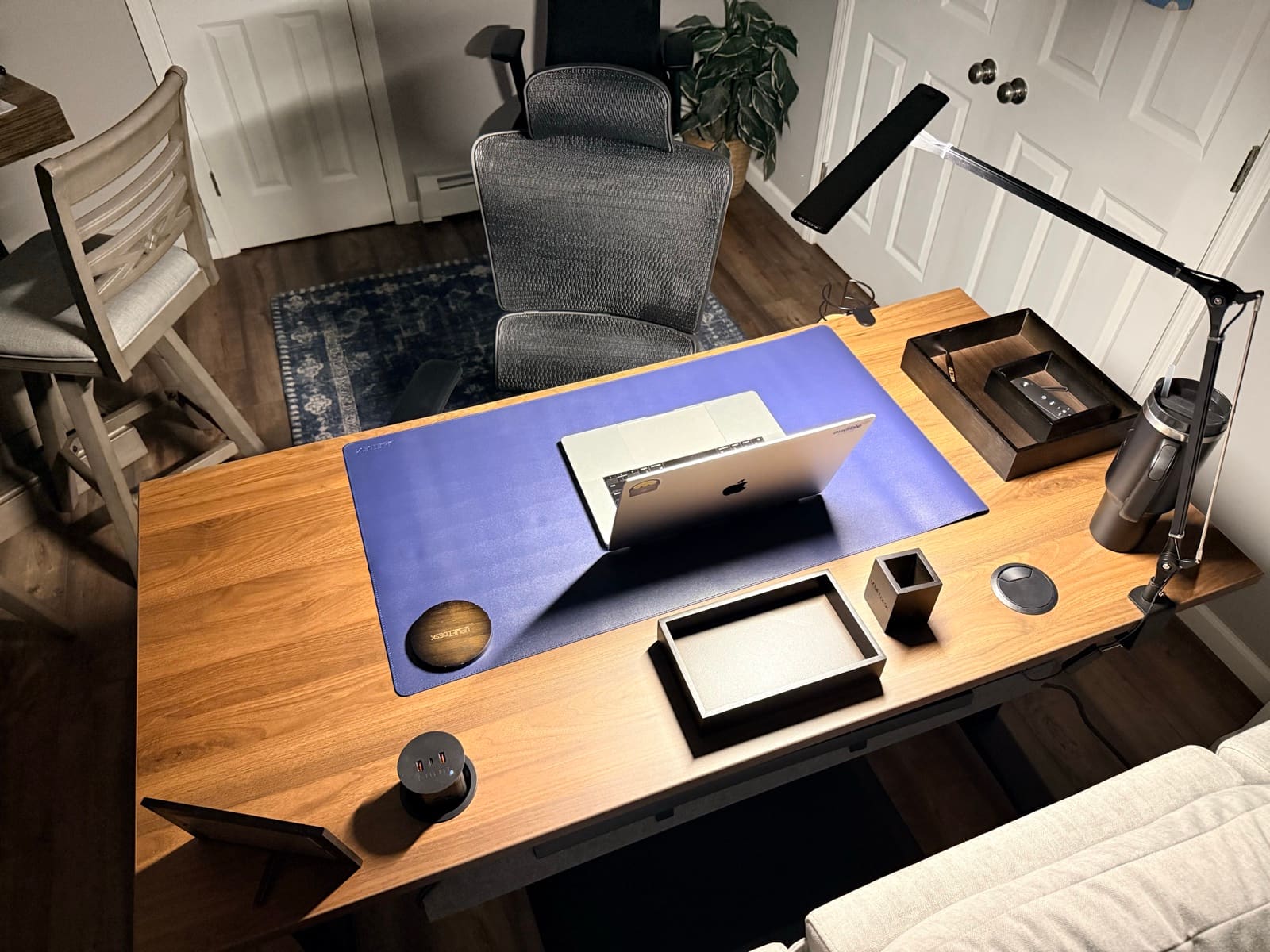 Overhead view of desk setup with laptop, desk mat, lamp, cup holder, and accessories